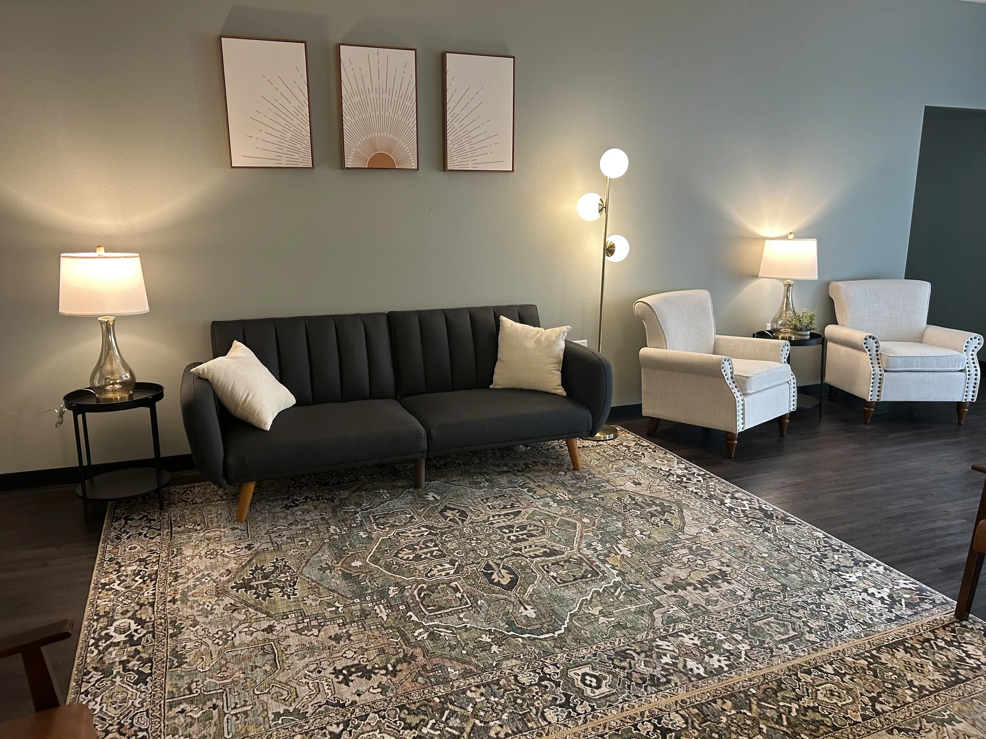 Dark sofa and two light armchairs in the shared Allis seating area
