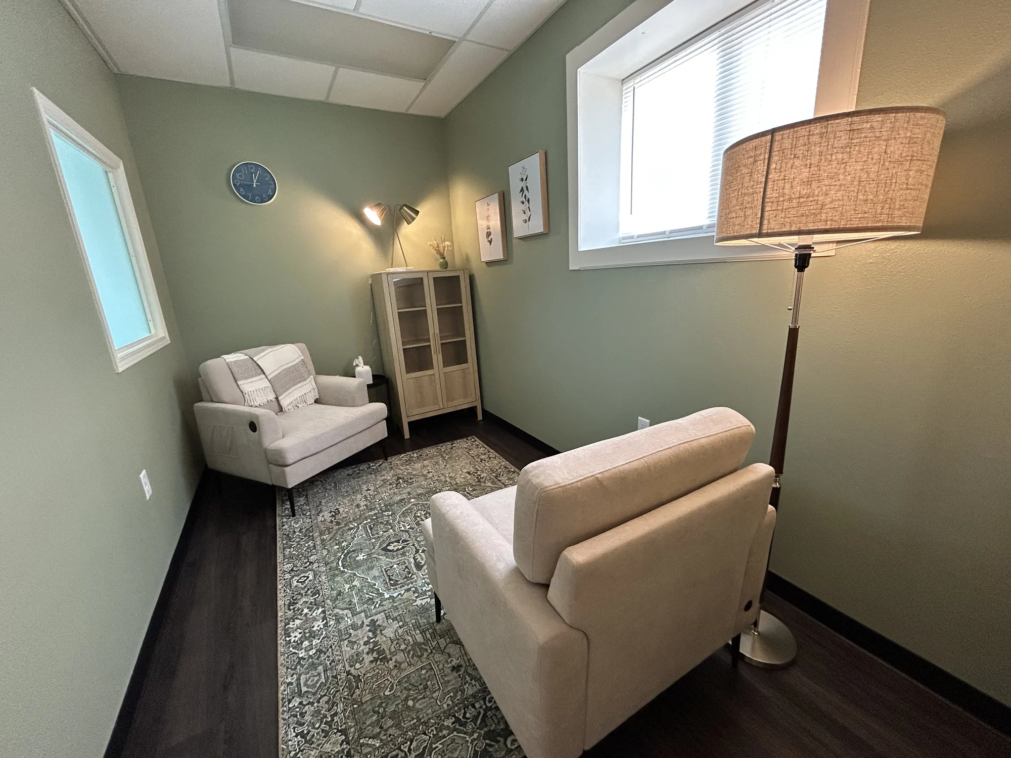 Two light armchairs with a cabinet and lamps in a smaller Allis room